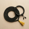 Black beaded necklace with a yellow tassel on a beige background