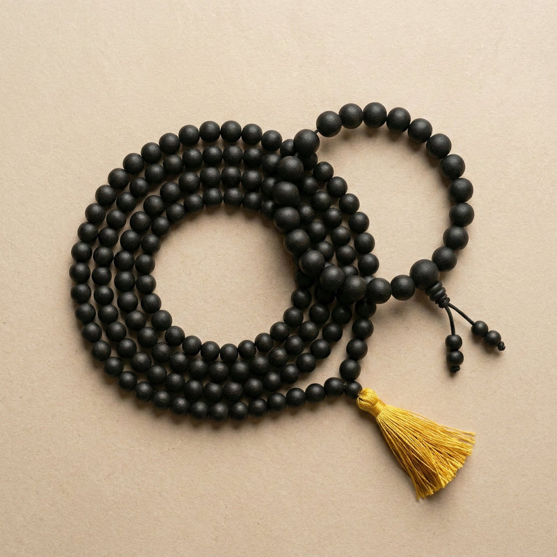 Black beaded necklace with a yellow tassel on a beige background