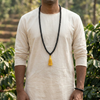Person wearing a long black beaded necklace with a yellow tassel outdoors.