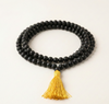 Black beaded necklace with a yellow tassel on a white background