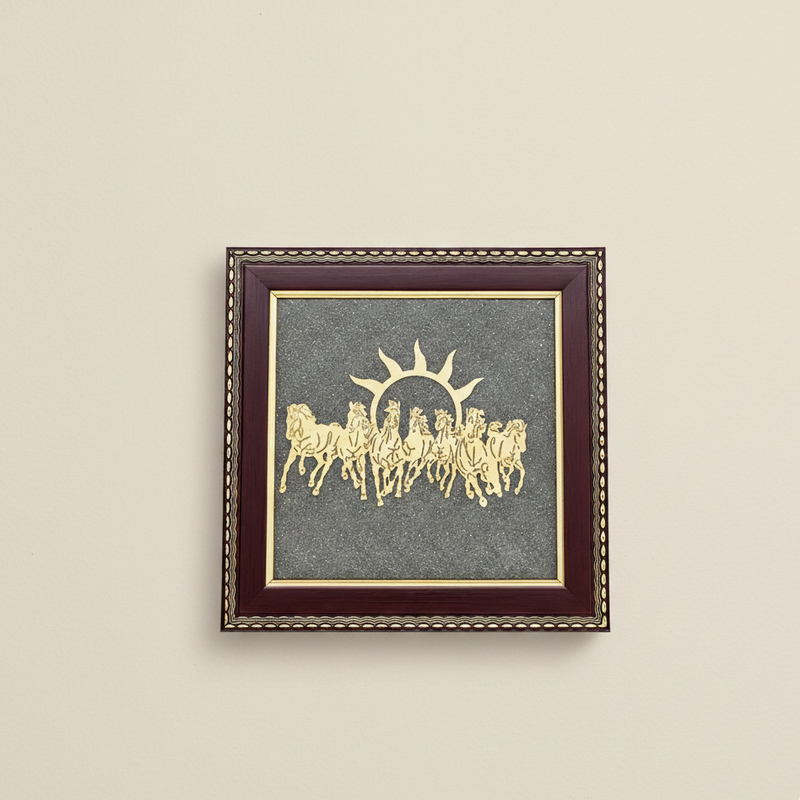 Framed artwork with a gold design on a gray background, mounted on a beige wall.