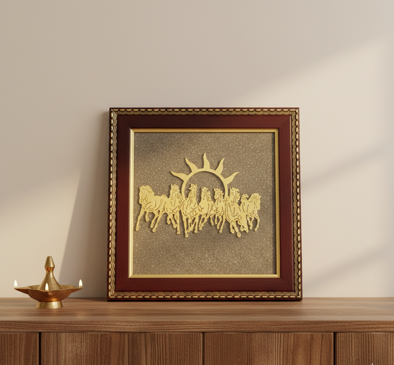 Decorative wall art with gold horses and sun design in a brown frame on a wooden surface.
