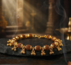 Gold bracelet with brown beads on a dark surface with smoke in the background