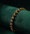 Gold bracelet with brown beads on a green cushion
