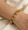 Gold and brown beaded bracelet on a wrist against a beige fabric background