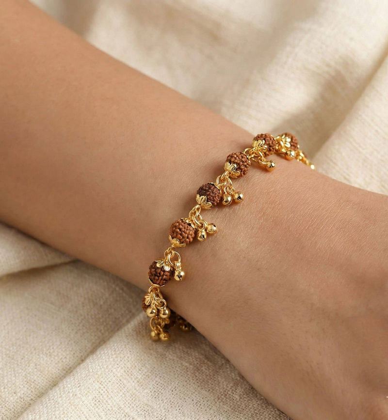 Gold and brown beaded bracelet on a wrist against a beige fabric background