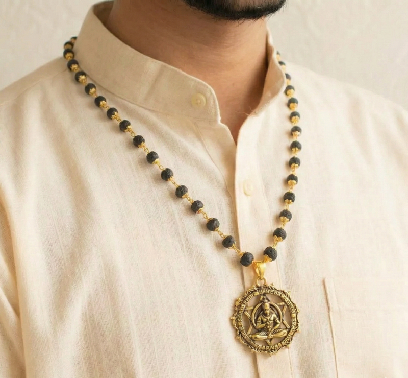 Man wearing a black and gold beaded necklace with a large pendant on a beige background