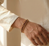Gold bracelet on a wrist with a neutral background