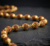 Necklace with gold and brown beads on a dark surface