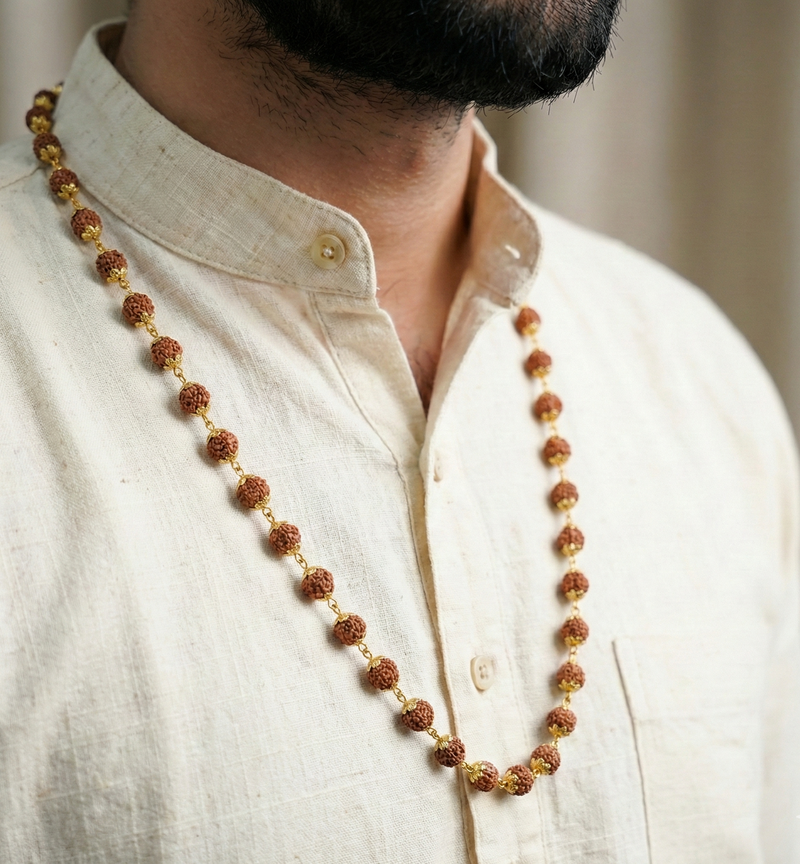Man wearing a long beaded necklace on a plain background