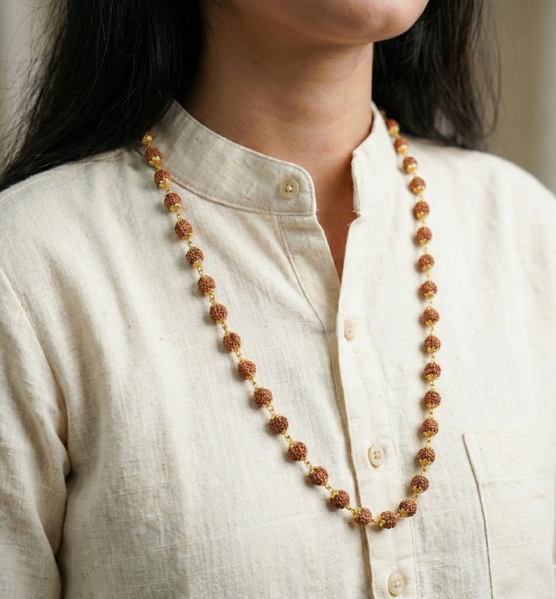 Person wearing a long beaded necklace on a neutral background