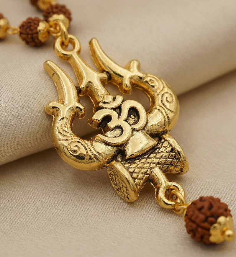 Gold necklace with intricate design and brown beads on a beige fabric background