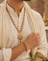 Person wearing a long beaded necklace and bracelet, with a blurred background