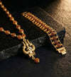 Gold necklace with rudraksha beads and a decorative pendant on a dark stone surface