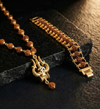 Gold necklace with rudraksha beads and a decorative pendant on a dark stone surface