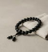 Black beaded bracelet on a beige surface with a white cloth
