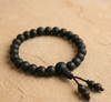 Black beaded bracelet on a beige surface
