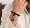 Person wearing a black beaded bracelet on a light background