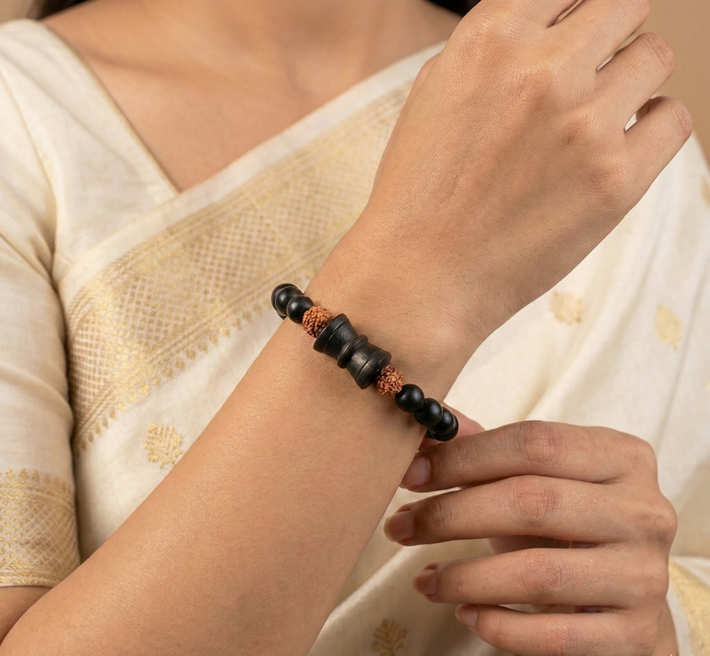 Person wearing a black beaded bracelet on a beige background