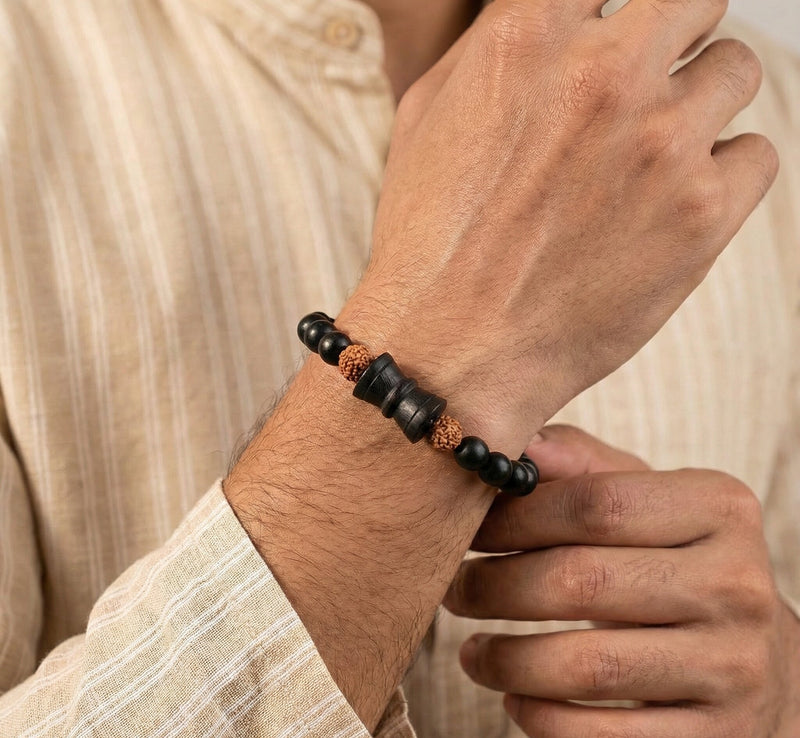Close-up of a person wearing a black beaded bracelet on a neutral background