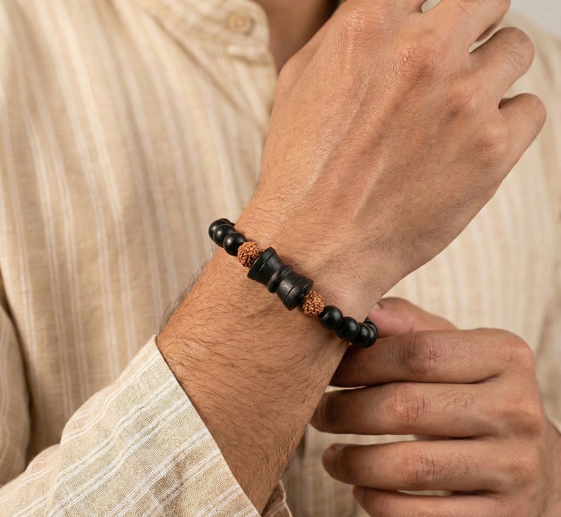 Close-up of a person wearing a black beaded bracelet on a neutral background