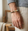 Person wearing a beaded bracelet on a blurred indoor background