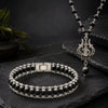 Black beaded bracelet and necklace with silver clasp on a dark stone surface