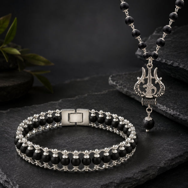 Black beaded bracelet and necklace with silver clasp on a dark stone surface