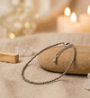 Silver bracelet on a stone with blurred candles and crystals in the background