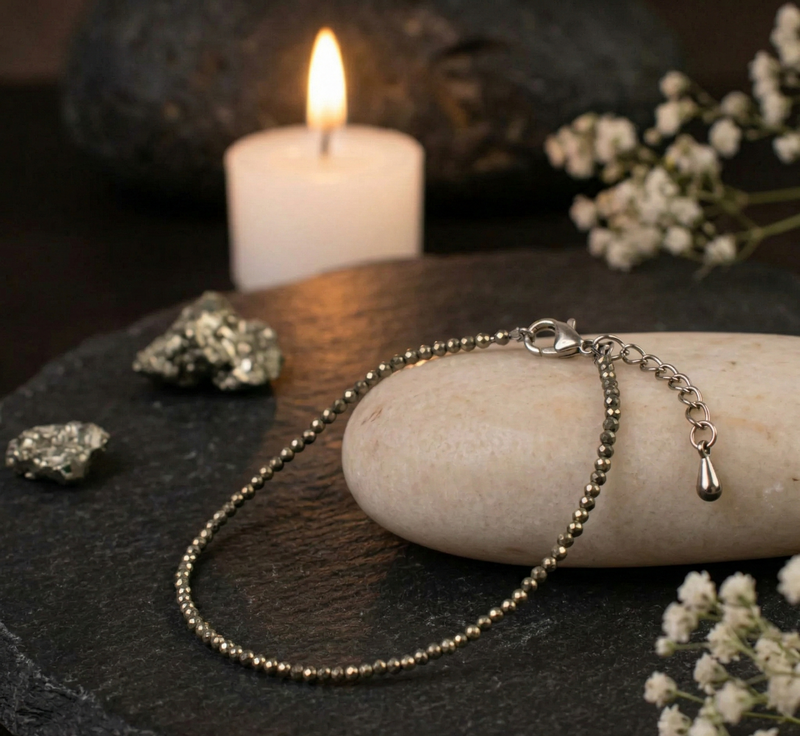 Silver bracelet on a stone with a candle and flowers in the background