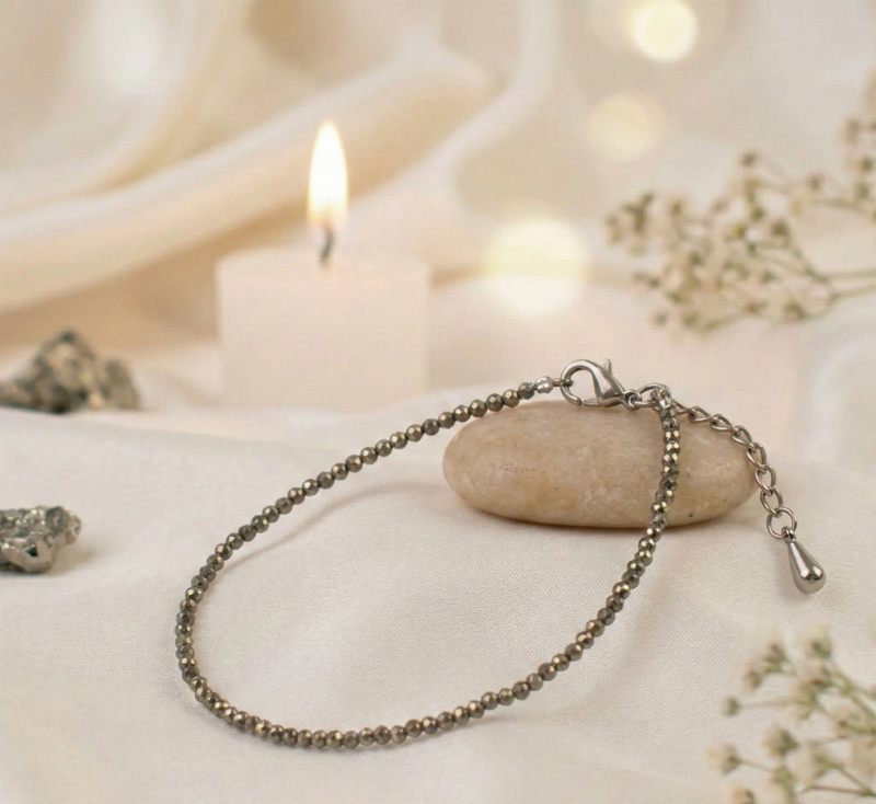Silver bracelet on a stone with a candle and flowers in the background