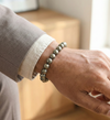 Hand wearing a silver beaded bracelet with a neutral background