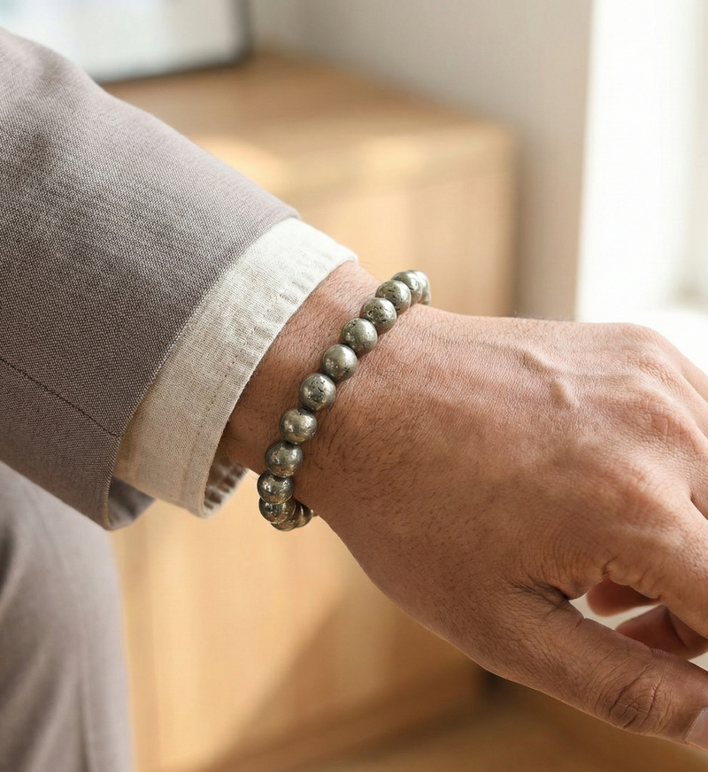 Hand wearing a silver beaded bracelet with a neutral background