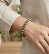 Person wearing a beaded bracelet on a blurred indoor background