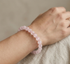 Pink beaded bracelet on a wrist against a neutral background