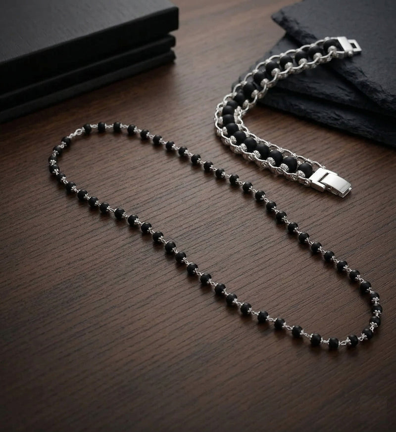 Black beaded necklace with silver chain on a wooden surface
