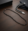 Black beaded necklace with silver chain on a wooden surface