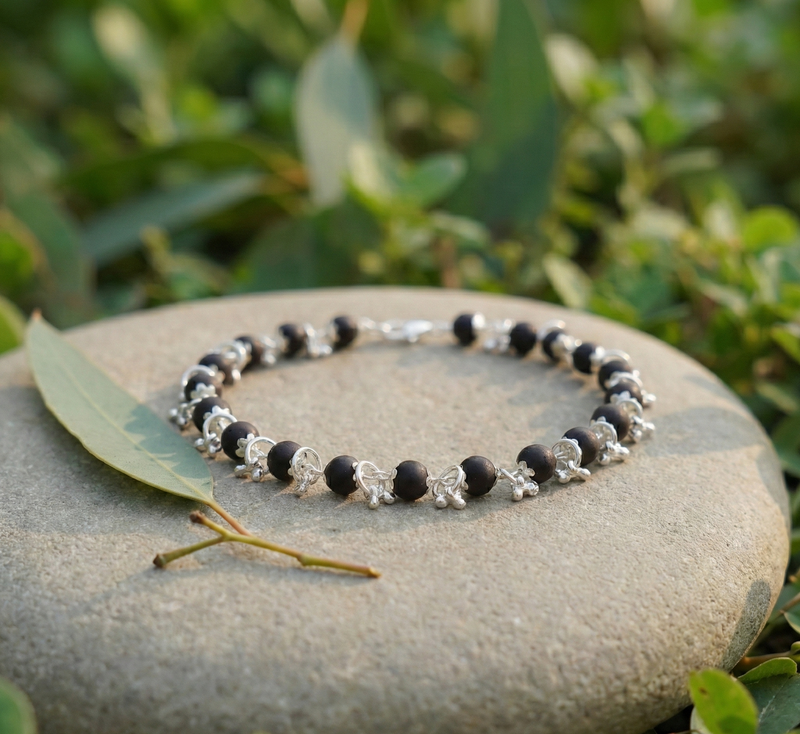 Necklace with black and silver beads on a stone with green foliage in the background