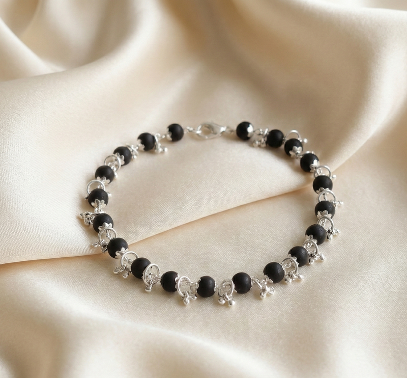 Black beaded bracelet on a beige fabric background