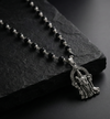 Black rosary with a silver pendant on a dark stone surface
