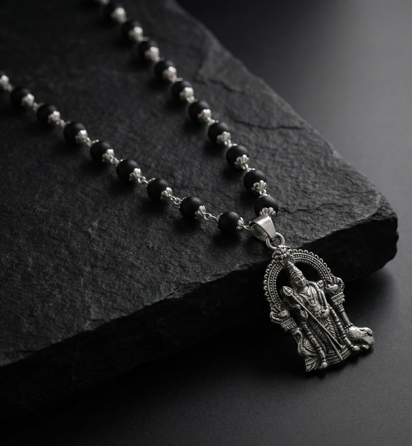 Black rosary with a silver pendant on a dark stone surface