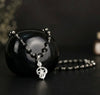 Black beaded necklace with silver pendant on a dark background