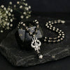 Black beaded necklace with a pendant on a dark stone surface