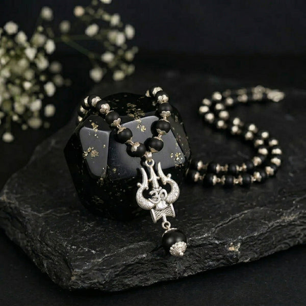 Black beaded necklace with a pendant on a dark stone surface