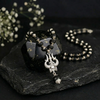 Black beaded necklace with a pendant on a dark stone surface