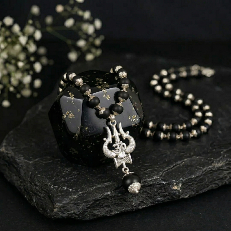 Black beaded necklace with a pendant on a dark stone surface
