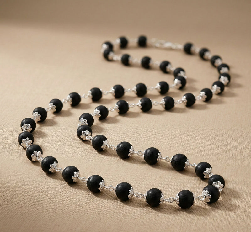 Necklace with black and silver beads on a beige fabric background