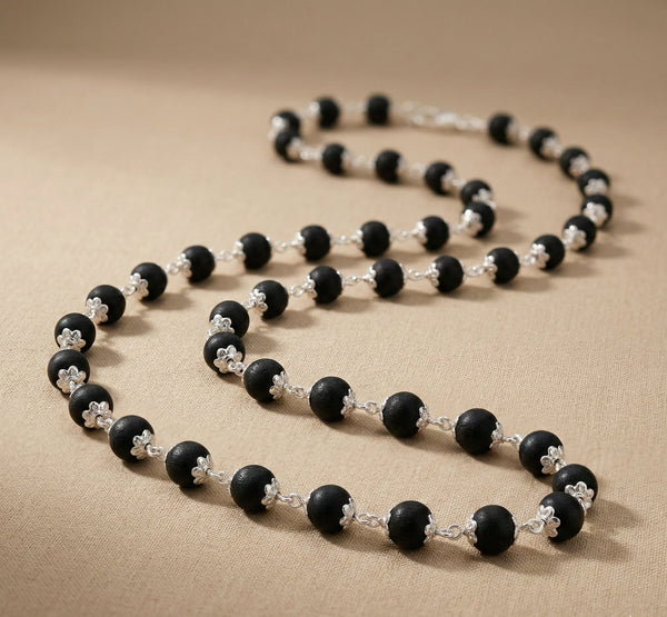 Necklace with black and silver beads on a beige fabric background
