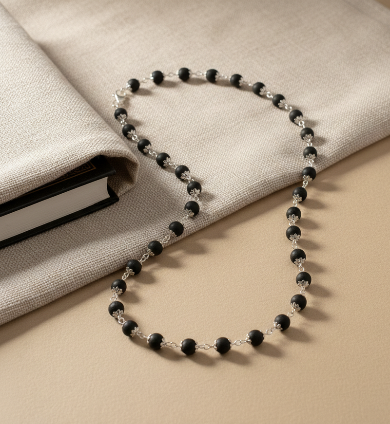 Black beaded necklace on a beige fabric surface
