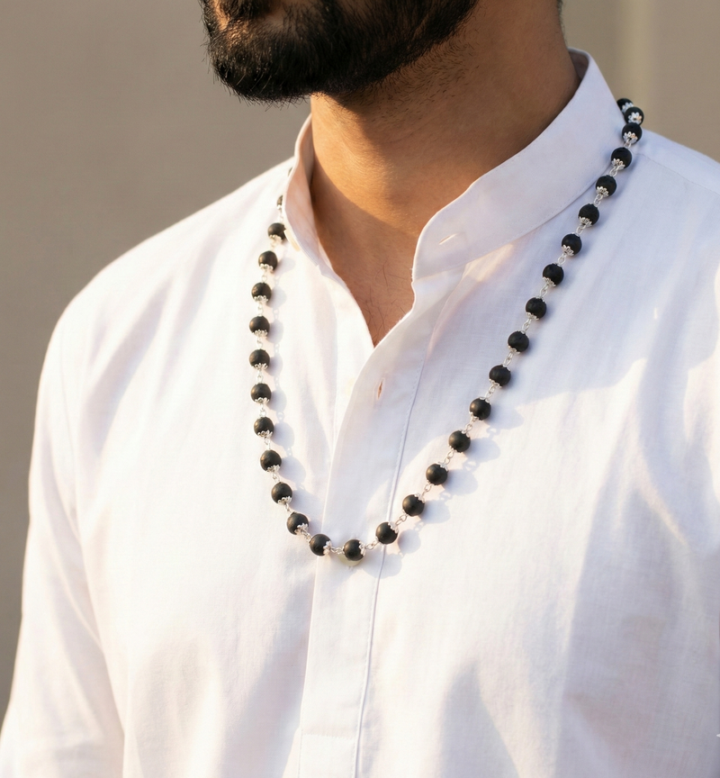 Man wearing a white shirt with a black beaded necklace